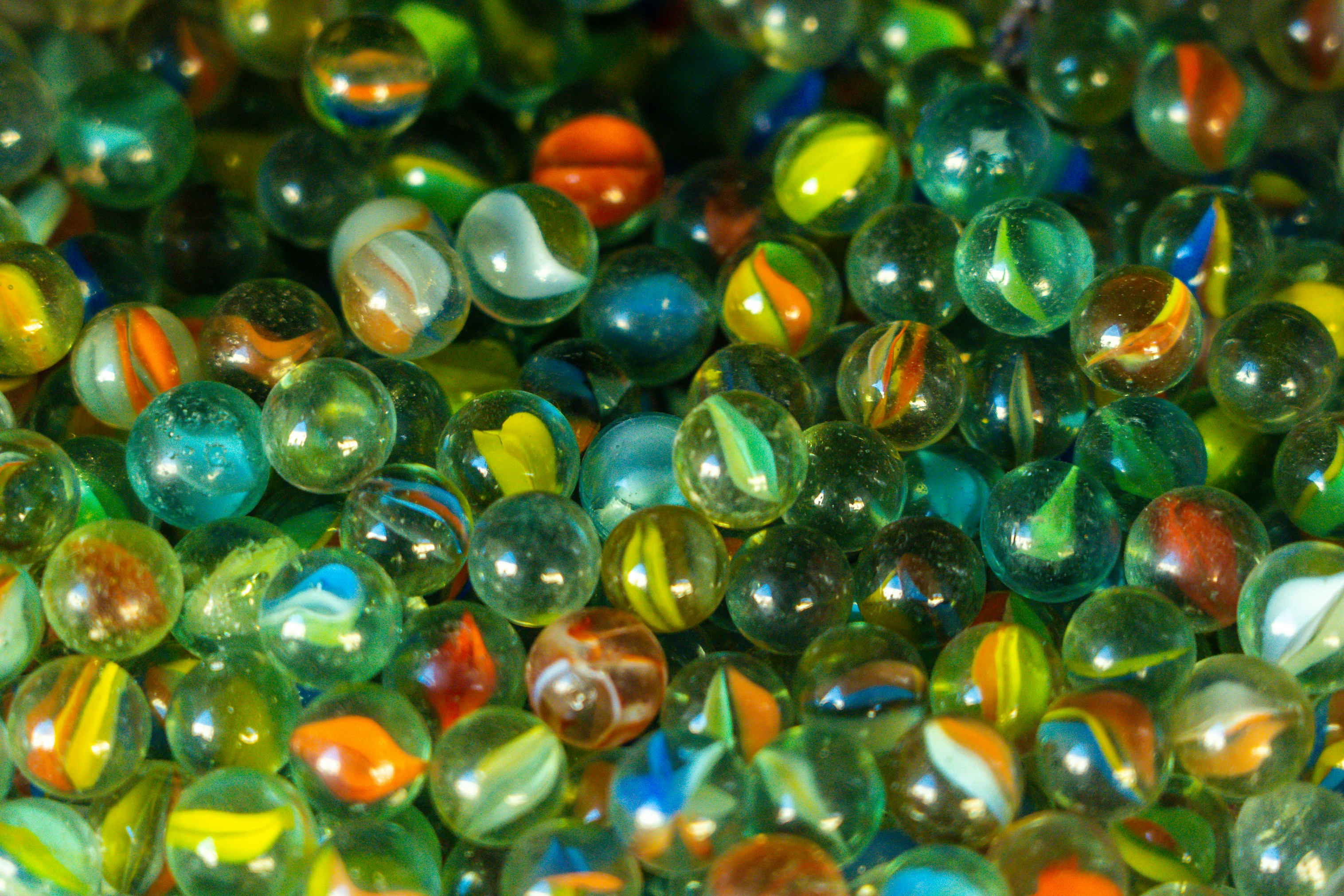 Billes de verre colorées en vue macro, chacune distincte mais formant ensemble une collection, métaphore du portefeuille incrémental : chaque livraison est une position qui s'accumule progressivement, pas en une seule mise